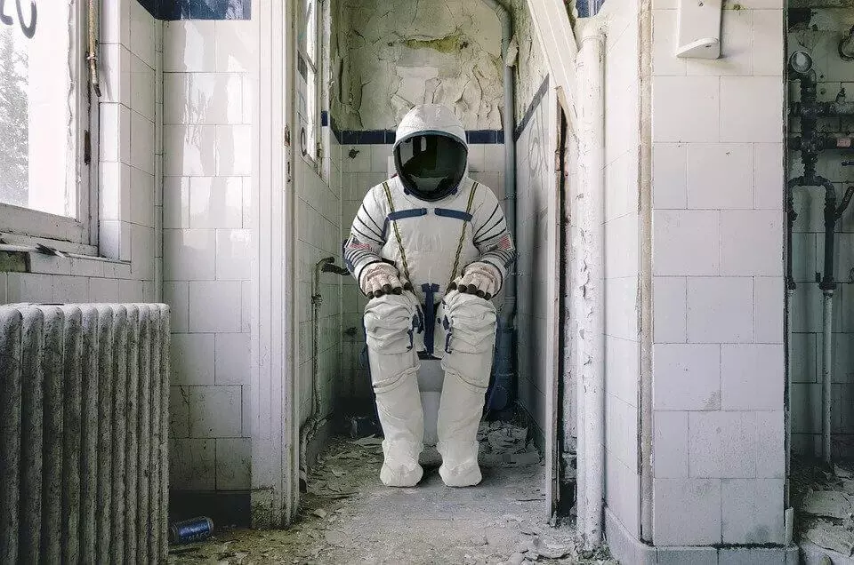 Man in spacesuit sitting on the toilet