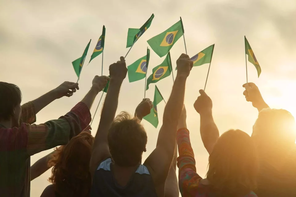A group of people holding Brazilian flags after moving internationally
