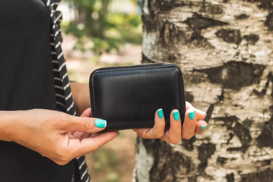A woman holding a black wallet after moving abroad