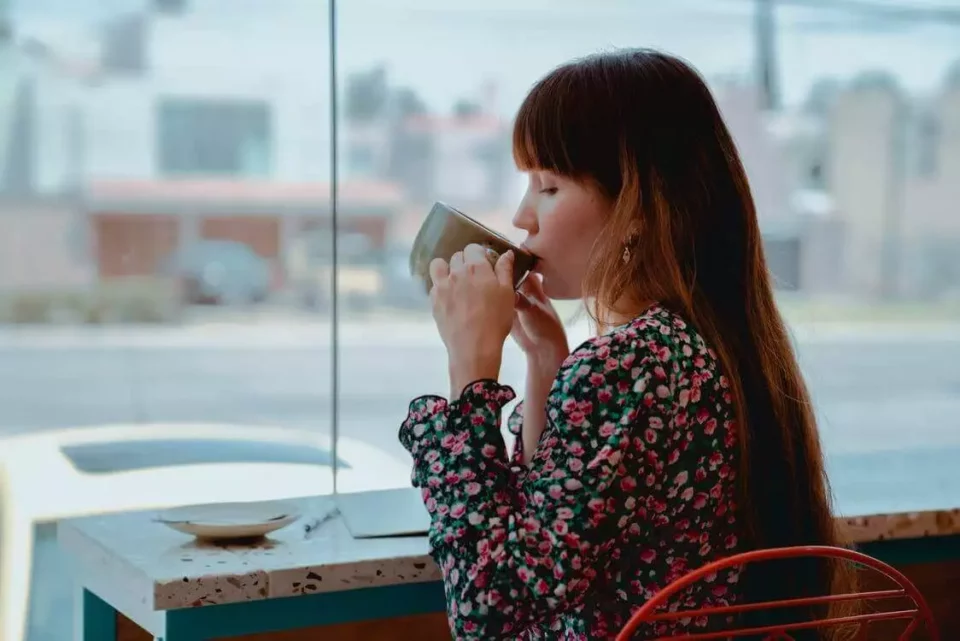 a woman drinking coffee from a large cup