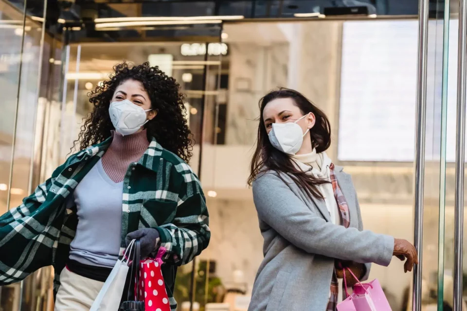 Two girls with masks exiting the shopping mall after overseas shipping of their downsized belongings