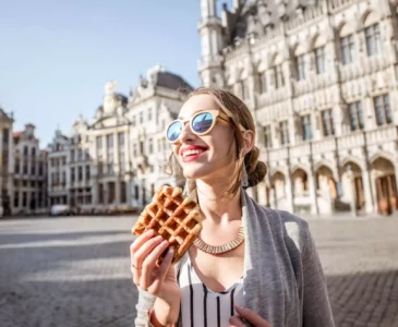 woman is eatng waffle in the center of brussels
