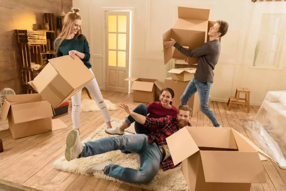 Four people having fun in a room full of boxes after moving internationally 