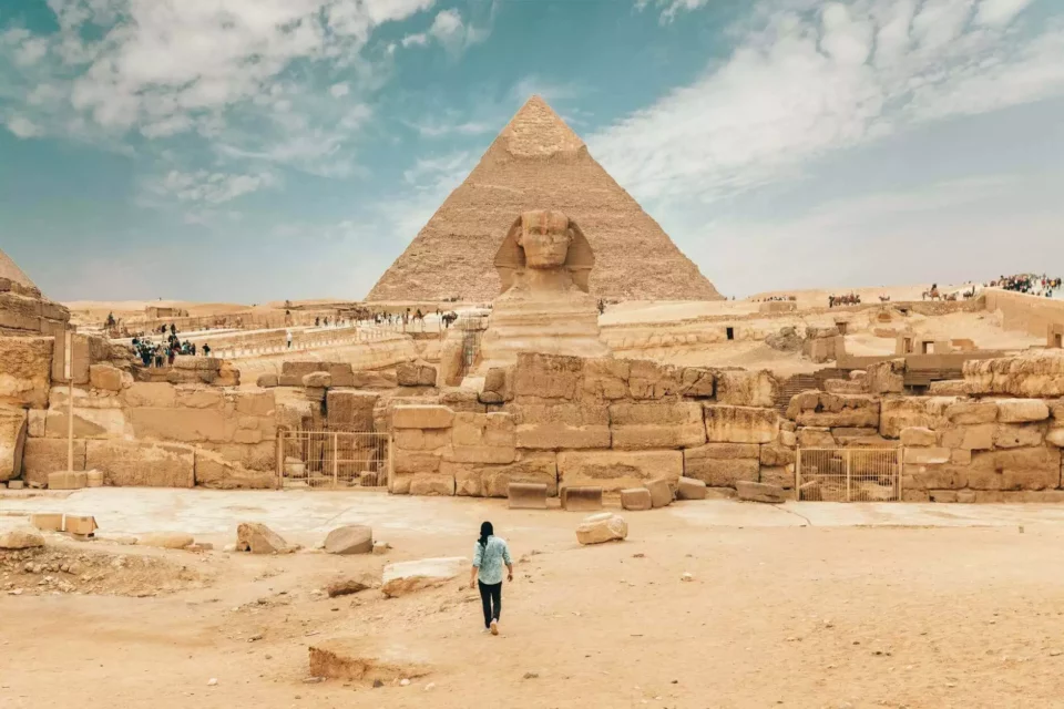 a man walking towards the Sphinx and the Pyramids in Egypt