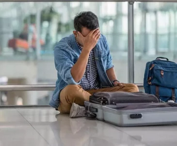 A man looking at his suitcase and holding his head