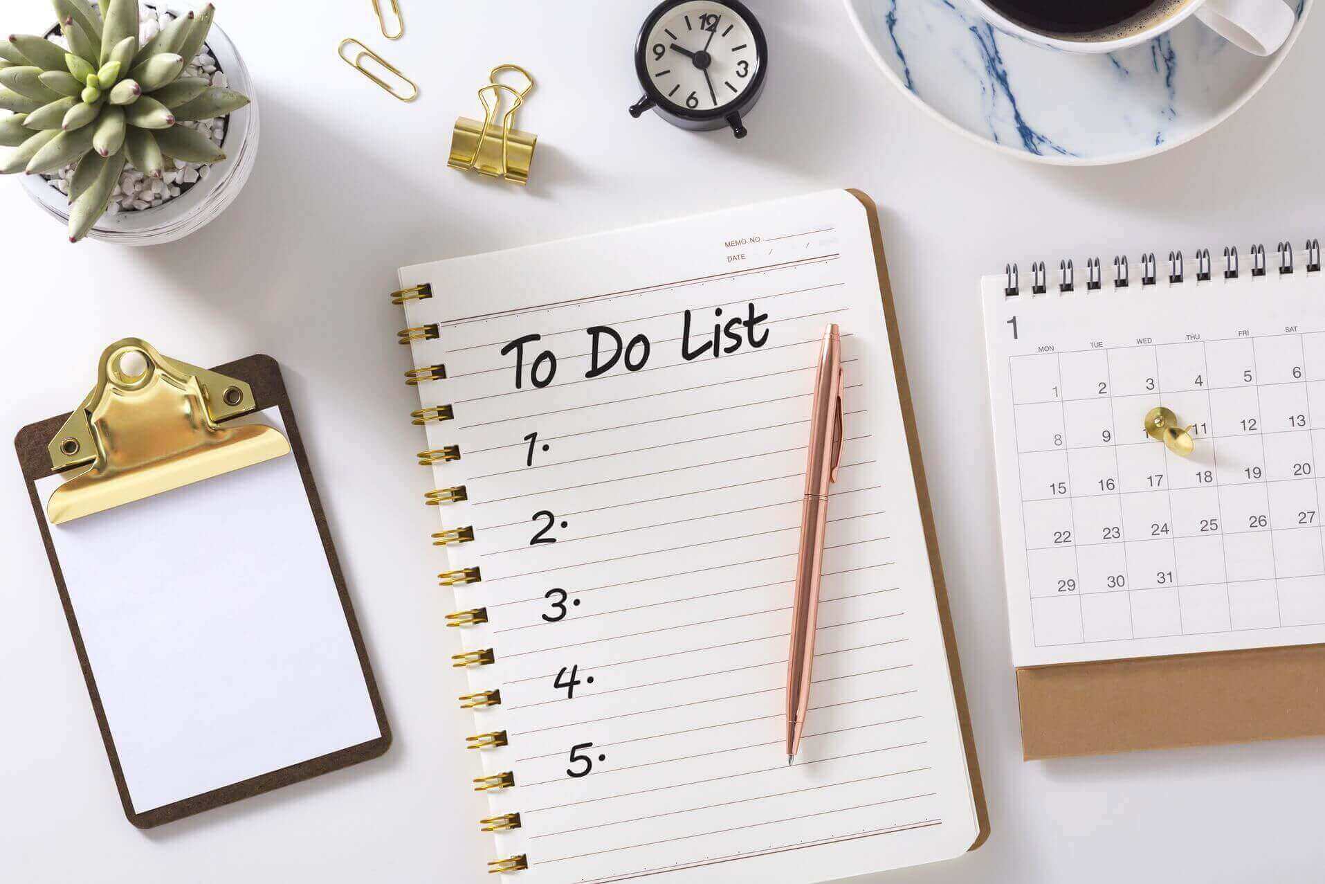 A to-do list, pen, plant, and calendar on the table