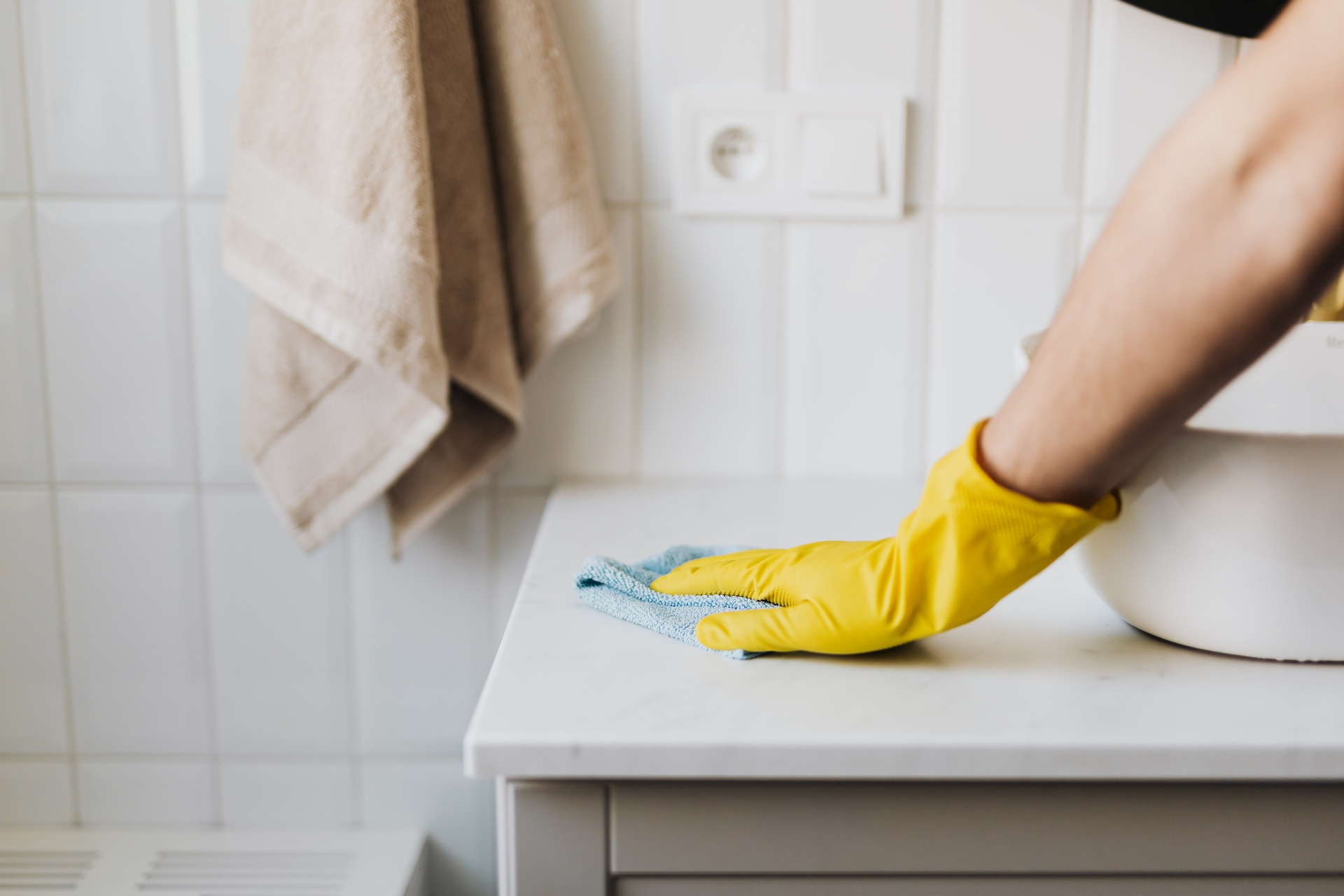 A woman in yellow gloves wiping the sink