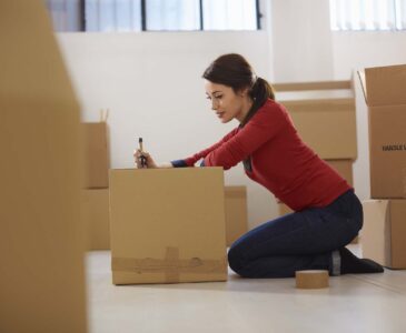 mid adult happy woman during move with boxes at new flat and packing carton