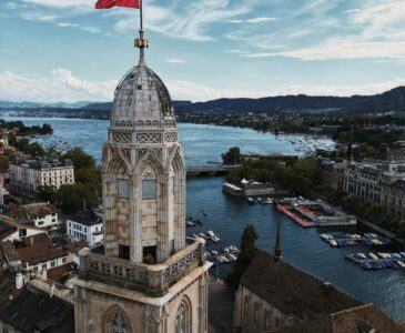 Large historic building with a flag by the water in Zurich Switzerland.